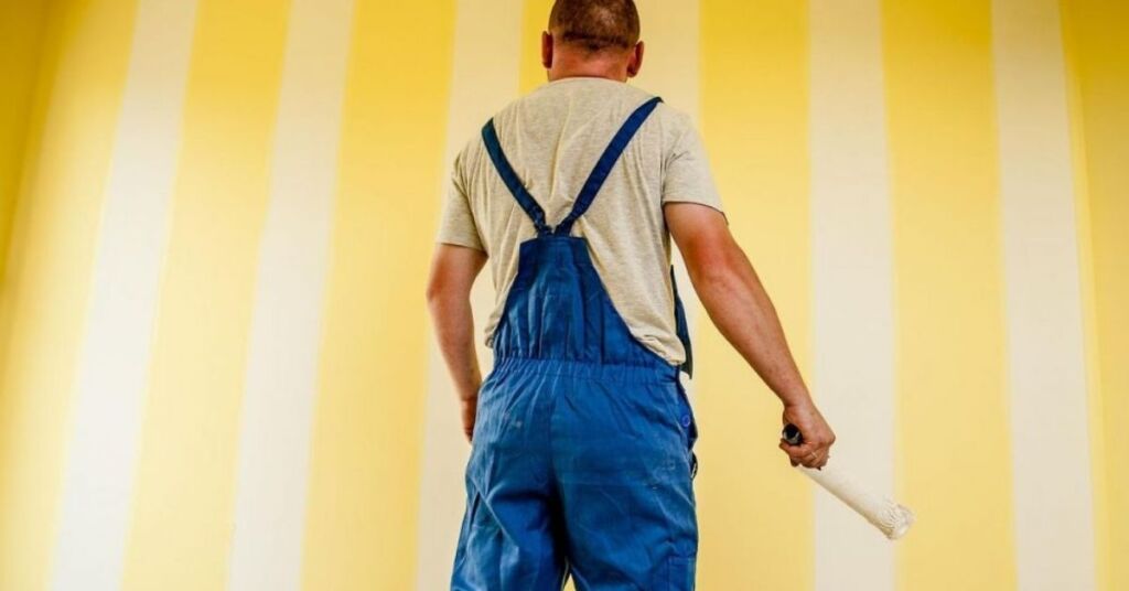 Maler som maler en væg med gul maling